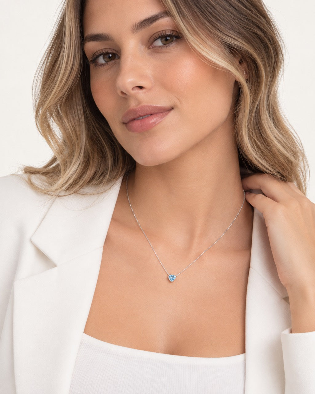 Modelo usando colar coração azul de 45 cm com blazer branco